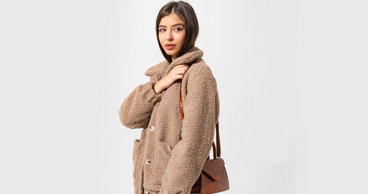 Woman wearing a cozy textured jacket with a structured handbag