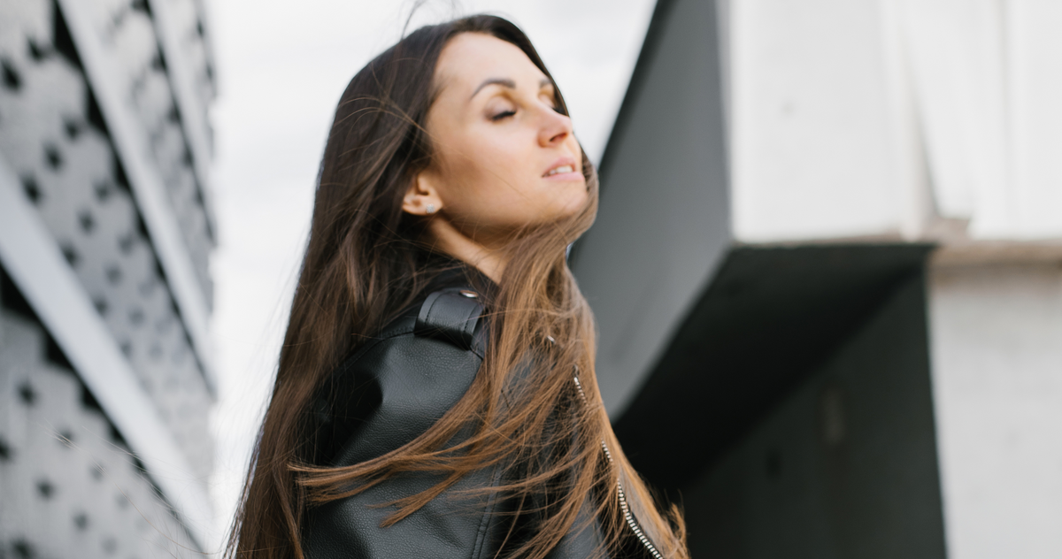 Woman wearing a sleek black jacket in an urban setting