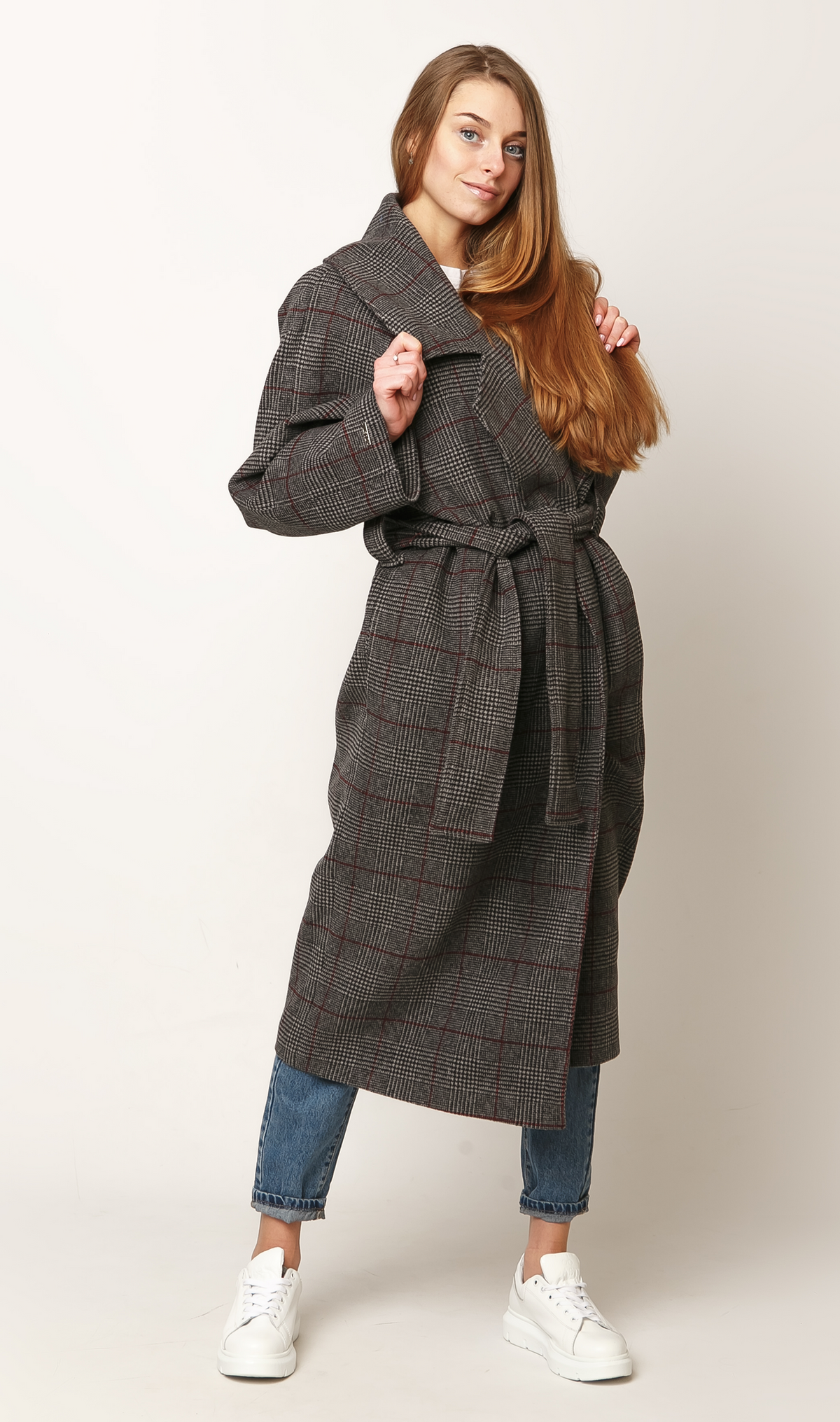 Model wearing a belted check coat with a longline silhouette