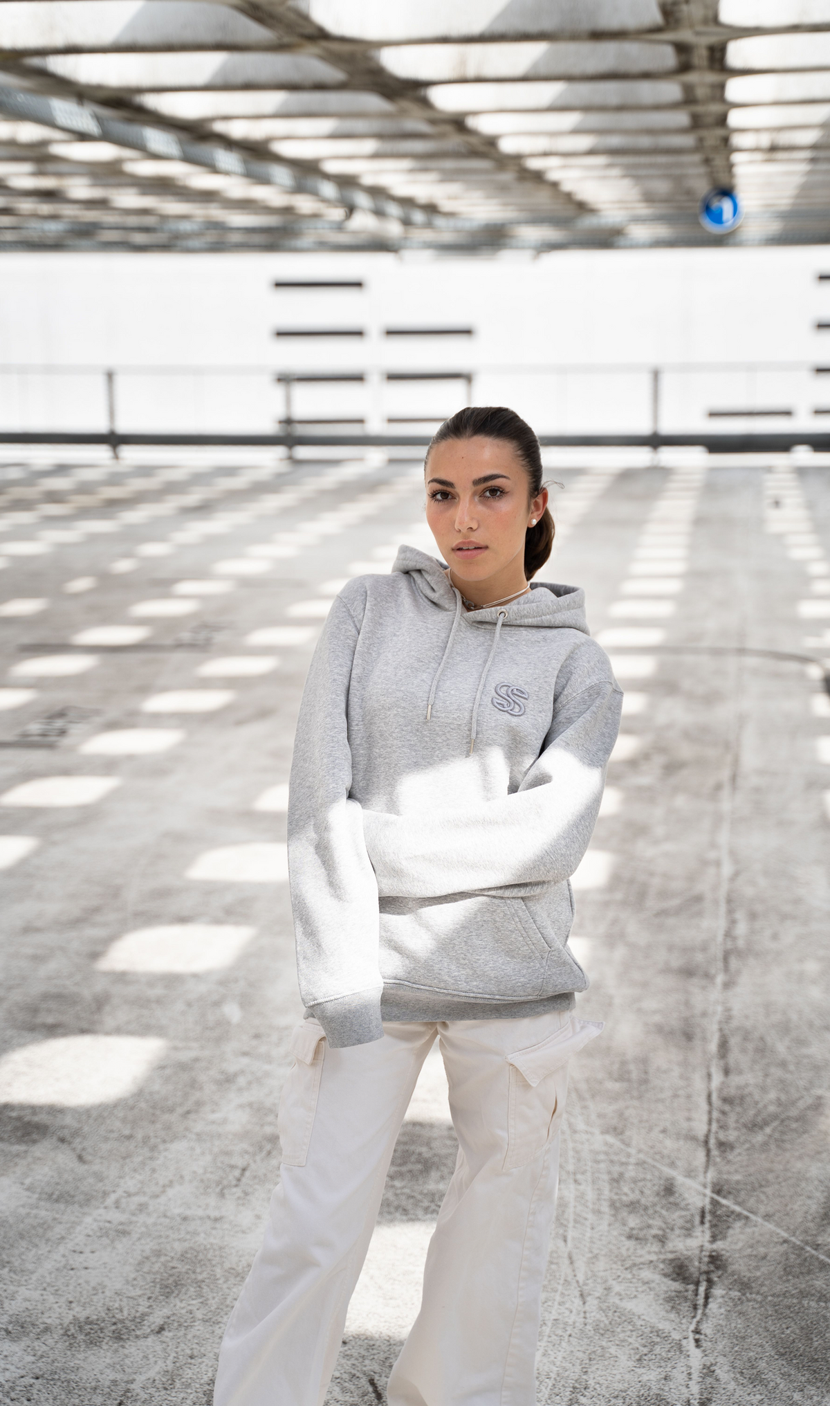 Model wearing a heritage logo hoodie with an adjustable hood and chest emblem