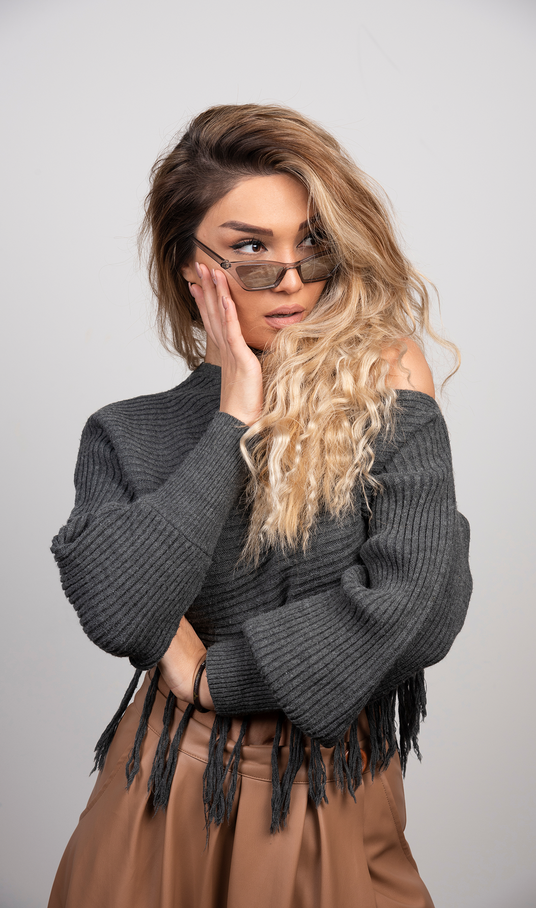 Model wearing a ribbed sweater with a relaxed fit, high neckline, and fringed hem