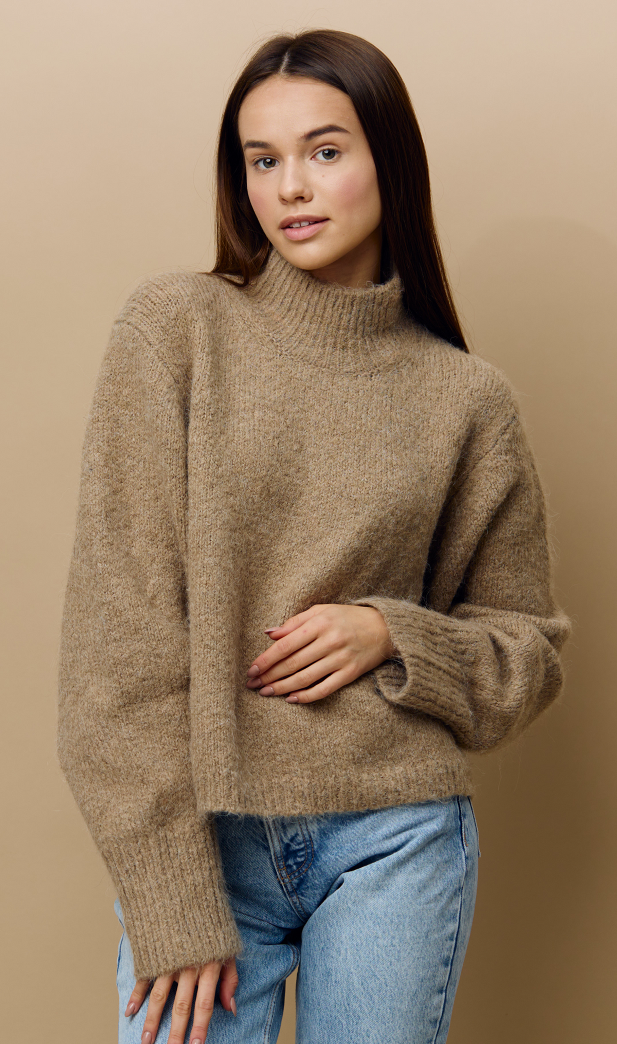 Model wearing a soft mock neck sweater with a relaxed fit and generous sleeves