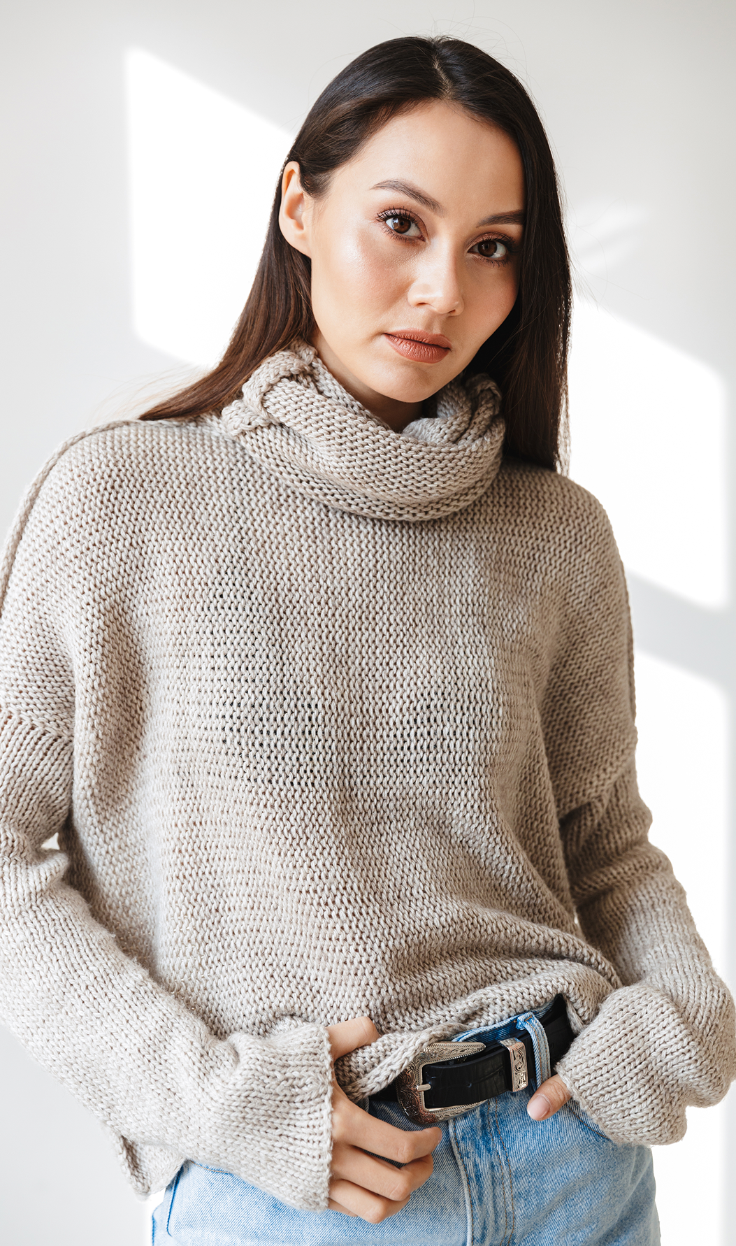 Model wearing a chunky cowl neck sweater with a relaxed fit and generous sleeves
