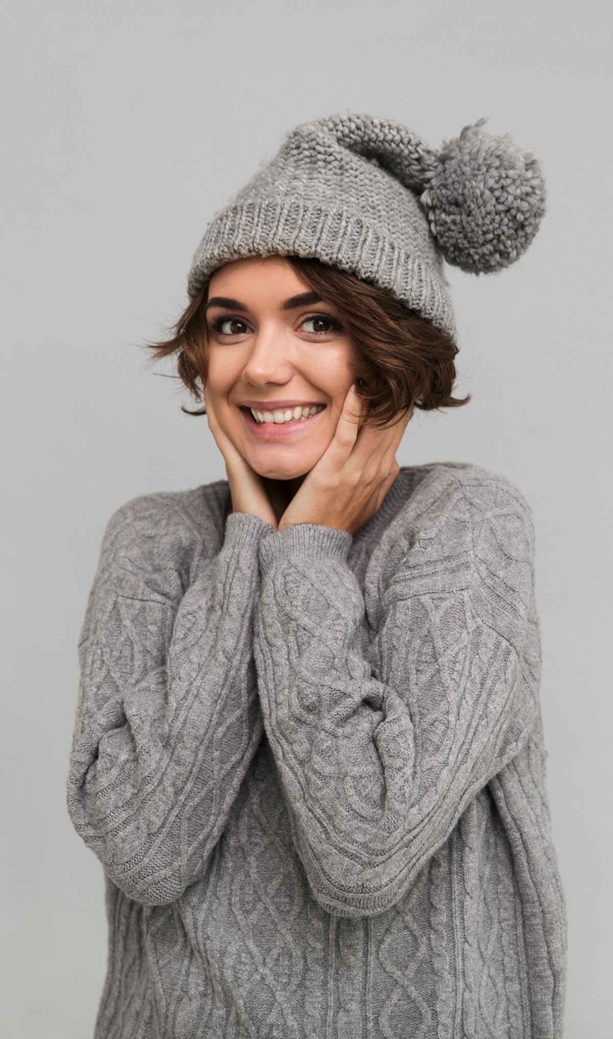 Cable knit pom beanie with a snug fold-over cuff and oversized pom detail