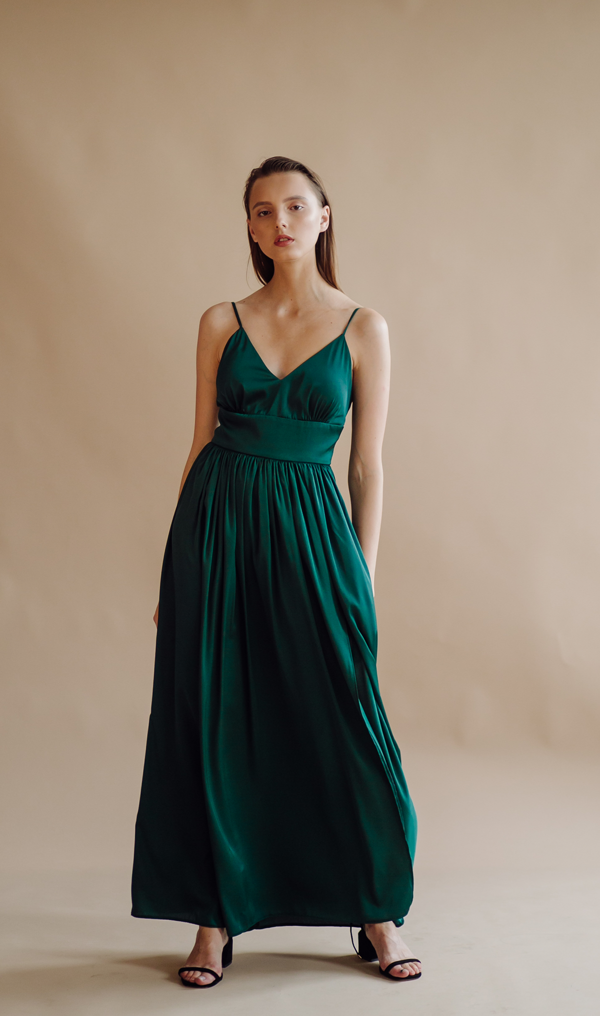 Model wearing a flowing full-length evening dress with delicate straps